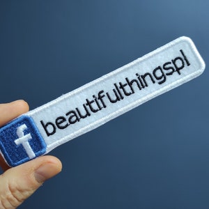 Könnte beinhalten: Weißer gestickter Aufnäher mit einem blauen Facebook-Logo und dem Text "beautifulthings" in Schwarz.
