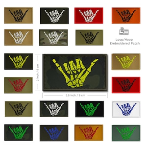 May include: A set of 16 embroidered patches featuring a skeleton hand making the shaka sign. The patches are available in a variety of colors and camouflage patterns. Each patch measures 2 inches by 3.5 inches. Loop/Hoop Embroidered Patch.