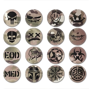 Può includere: Set di 16 patch rotondi mimetici con vari disegni grafici neri. I patch presentano teschi, facce sorridenti, ossa incrociate e altri simboli.