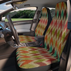 May include: Car seat covers with a colorful geometric pattern. The design features a repeating pattern of diamond shapes in shades of red, orange, green, and teal on a beige background. The covers are installed in a car interior.