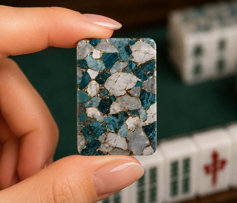 May include: A rectangular mahjong tile featuring a mosaic pattern of white and deep teal stone fragments held together by thin gold-colored veins. The surface is smooth and polished, displaying a complex, multi-faceted appearance with sharp edges.