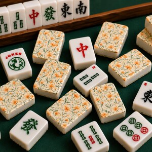 May include: A collection of Mahjong tiles featuring a mix of white tiles with orange floral patterns and traditional tiles with red, green, and black Chinese characters or symbols. One tile is labeled JOKER with a green dragon graphic.