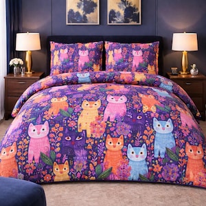 May include: A vibrant cat-themed duvet cover and pillowcase set. The purple bedding features a repeating pattern of cartoon cats in various colours, including orange, pink, and blue, amongst floral designs. The set is displayed on a bed with bedside lamps.