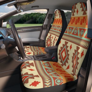 Puede incluir: Fundas de asiento de coche con un patrón geométrico del suroeste en tonos beige, marrón, naranja y turquesa. Las fundas están instaladas en un coche, con el volante y el salpicadero visibles. El diseño presenta formas de diamante y triángulo.