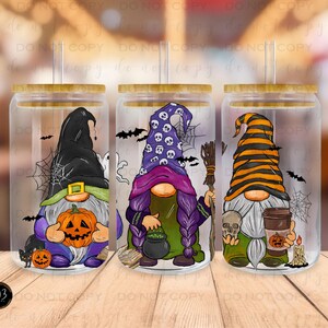 May include: Three clear glass tumblers with lids and straws, each featuring a different Halloween gnome design. The gnomes are wearing hats and holding various Halloween-themed items, including a pumpkin, a cauldron, and a coffee cup.
