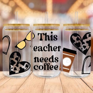 May include: Three clear glass tumblers with bamboo lids and straws. The tumblers have different designs: one has a heart with a cow print, sunglasses, and a heart with a cow print, another has the text "This teacher needs coffee", and the last one has a heart with a cow print, a coffee cup, and a heart with a cow print.