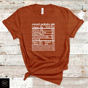 May include: A brown t-shirt with a white graphic that reads "sweet potato pie" and lists nutritional information. The text includes "Calories 266", "Total Fat 11g", "Cholesterol 0mg", "Sodium 490mg", "Total Carbohydrate 25g", "Protein 4g", "Vitamin A 95%", "Vitamin C 5%", "Calcium 12%", and "Iron 7%". The graphic also includes a humorous Thanksgiving-themed message.