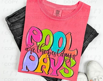 May include: A pink t-shirt with the text "Pool are the best days" in colorful, bubble-like letters. The shirt is folded and displayed on a pair of jeans.