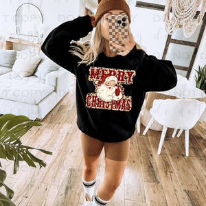 May include: Black sweatshirt with a red and white "Merry Christmas" graphic featuring a cartoon Santa Claus with a leopard print background.