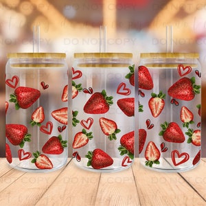 May include: Three clear glass tumblers with bamboo lids and straws. Each tumbler features a pattern of red strawberries and hearts on a white background.