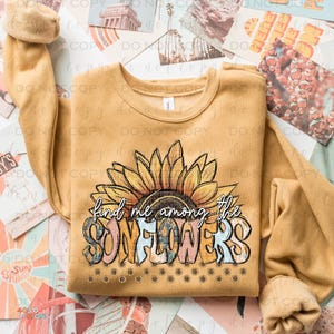May include: A mustard yellow sweatshirt with a graphic of a sunflower and the text "find me among the sunflowers".