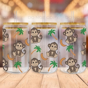May include: Three clear glass tumblers with bamboo lids and straws. Each tumbler features a repeating pattern of monkeys, palm trees, and bananas.