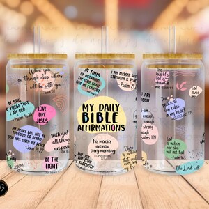 May include: Three clear glass tumblers with bamboo lids and straws. Each tumbler has a different design with inspirational bible verses and quotes. The tumblers are decorated with colorful circles and text.