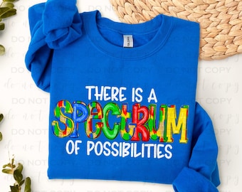 May include: A royal blue long-sleeved shirt with the text "There is a Spectrum of Possibilities" in white. The word "Spectrum" is in rainbow colors with a tie-dye pattern.