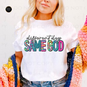 May include: White t-shirt with a colorful graphic design that says "different day SAME GOD".