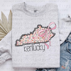May include: A gray sweatshirt with a floral design of the state of Kentucky with a pink bow on top. The word "kentucky" is written in black below the state outline.