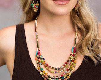 May include: A multi-strand necklace with colorful fabric-covered beads and gold accents. The necklace is layered and features a variety of colors, including red, green, blue, yellow, and orange.
