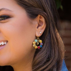 May include: A pair of gold hoop earrings with colorful fabric circles. The earrings are made of recycled materials and are a unique and stylish accessory.