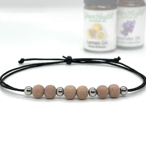 May include: A black string bracelet with six wooden beads and silver metal beads.