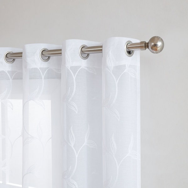 Rideaux blancs transparents avec broderie de feuilles élégantes. Les rideaux à feuilles sont livrés avec des surpiqûres anthracite, lin, argentées et blanches. Disponible en 3 tailles.