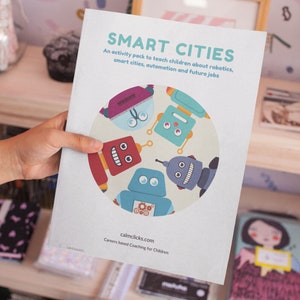 Peut inclure: Une brochure bleue et blanche intitulée "SMART CITIES" avec un cercle de robots colorés sur la couverture. Le texte sous le cercle indique "Un pack d'activités pour apprendre aux enfants la robotique, les villes intelligentes, l'automatisation et les emplois du futur". Le bas de la brochure indique "calmclicks.com Coaching pour les carrières basé sur les enfants".