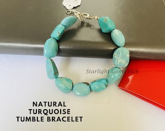 May include: A turquoise gemstone bracelet with a silver clasp. The bracelet is made of natural turquoise tumble stones. The text "NATURAL TURQUOISE TUMBLE BRACELET" is printed below the bracelet.