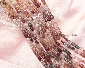 May include: A strand of pink, purple, and clear gemstone beads. The beads are oval shaped and have a smooth, polished finish. The beads are strung on a clear thread and are ready to be used for jewelry making.