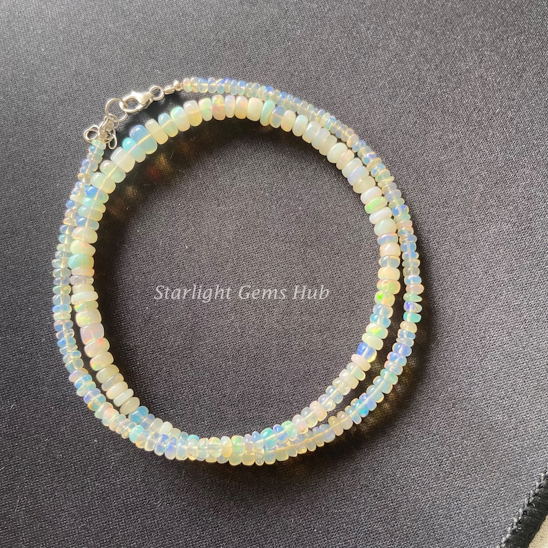 May include: A double strand necklace made of iridescent white opal beads. The necklace is strung on a silver chain with a lobster clasp.