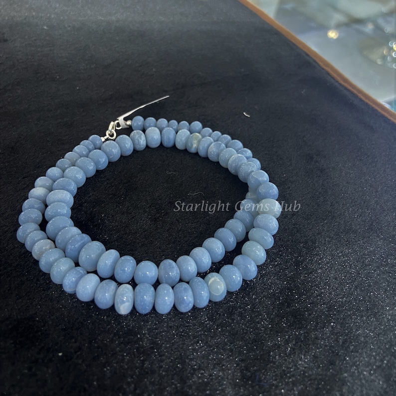 May include: A light blue gemstone bead necklace with a silver clasp. The beads are round and smooth, and the necklace is approximately 18 inches long.