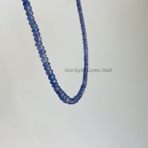 May include: A strand of light blue gemstone beads, strung on a thin wire. The beads are faceted and have a slightly irregular shape. The strand is hanging in a loop, with the ends of the wire visible.