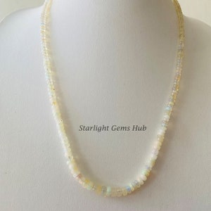 May include: A white opal bead necklace with a delicate design. The necklace is made of small, round beads that are strung together on a thin chain. The beads are a pale white color with a slight iridescent sheen. The necklace is approximately 18 inches long.