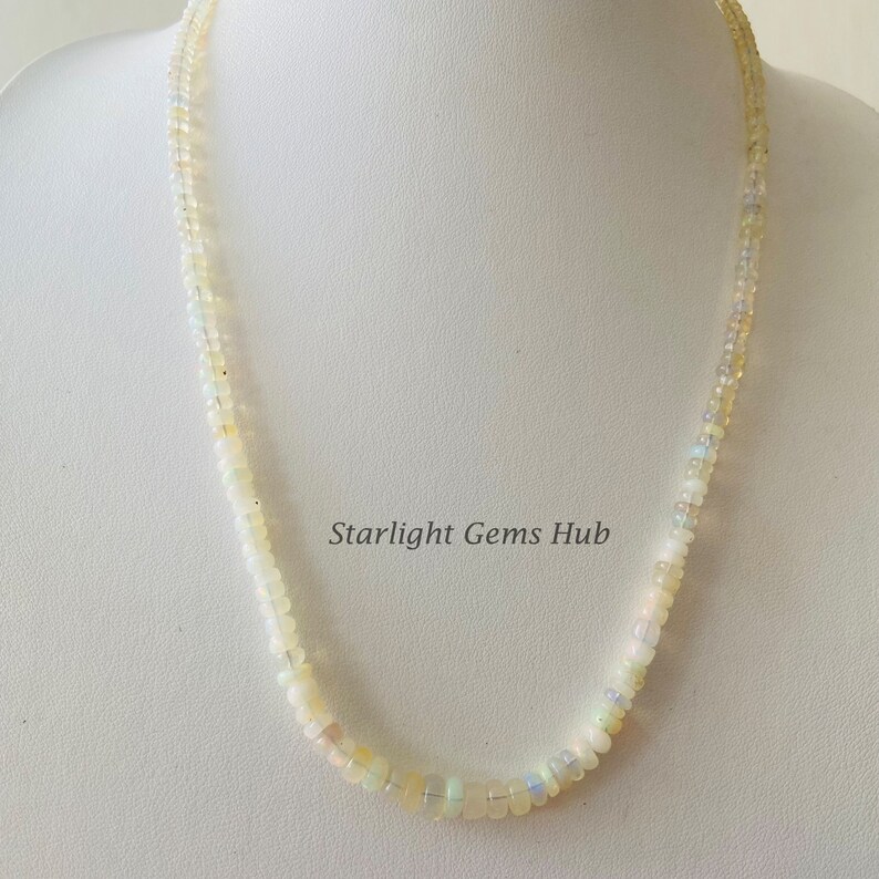 May include: A white opal bead necklace with a delicate design. The necklace is made of small, round beads that are strung together on a thin chain. The beads are a pale white color with a slight iridescent sheen. The necklace is approximately 18 inches long.