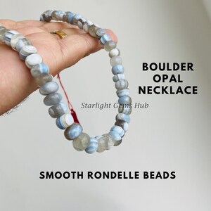May include: A Boulder Opal necklace with smooth rondelle beads in grey, white, and blue. The necklace is shown against a light background. The text "BOULDER OPAL NECKLACE" and "SMOOTH RONDELLE BEADS" are visible.