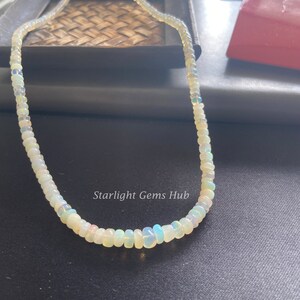 May include: A white opal bead necklace with a silver clasp. The necklace is made of small, round beads that are strung together on a thin silver chain. The necklace is about 18 inches long and is perfect for everyday wear.