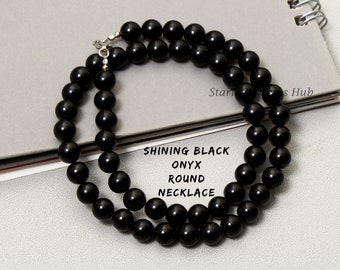 Puede incluir: Un collar de cuentas redondas de ónix negro. El collar está hecho de cuentas de ónix negro lisas y pulidas. Las cuentas están enhebradas en una cadena de plata.
