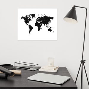 Può includere: Stampa di una mappa del mondo in bianco e nero. I continenti sono raffigurati in nero pieno su sfondo bianco. La stampa è esposta sopra una scrivania con un laptop, una candela e altri oggetti.