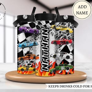 以下が含まれることがあります： チェック柄のレーシングテーマのパーソナライズされたウォーターボトル3本。ボトルにはさまざまなレーシングカーが描かれており、中央のボトルには「NATHAN」という名前が印刷されています。