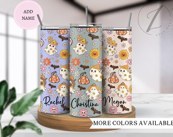 May include: Three stainless steel tumblers with personalised names "Rachel", "Christina", and "Megan". The tumblers feature a Halloween-themed design with ghosts, pumpkins, bats, and flowers in shades of purple, orange, yellow, and green.