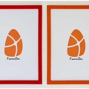 May include: Two framed prints with a white background and an orange egg-shaped design. The frames are red and orange, and the text "FramesDen" is at the bottom of each print.