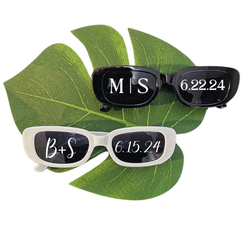 May include: Two pairs of sunglasses with white text on the lenses. The top pair is black with the text "M|S 6.22.24". The bottom pair is white with the text "B+S 6.15.24".
