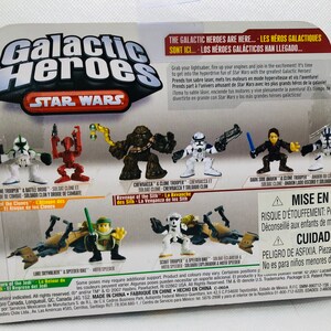 May include: A set of Star Wars Galactic Heroes action figures. The figures include Chewbacca, a Clone Trooper, a Dark Anakin, and a Speeder Bike. The packaging features the Star Wars logo and the Galactic Heroes logo.