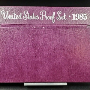 May include: A purple, textured, cardboard box with the text "United States Proof Set - 1985" printed in white.