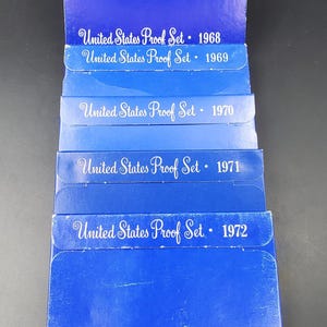 May include: A collection of United States Proof Sets from 1968 to 1972. The sets are in blue packaging, with the years printed in white. The text "United States Proof Set" is also visible on each package.