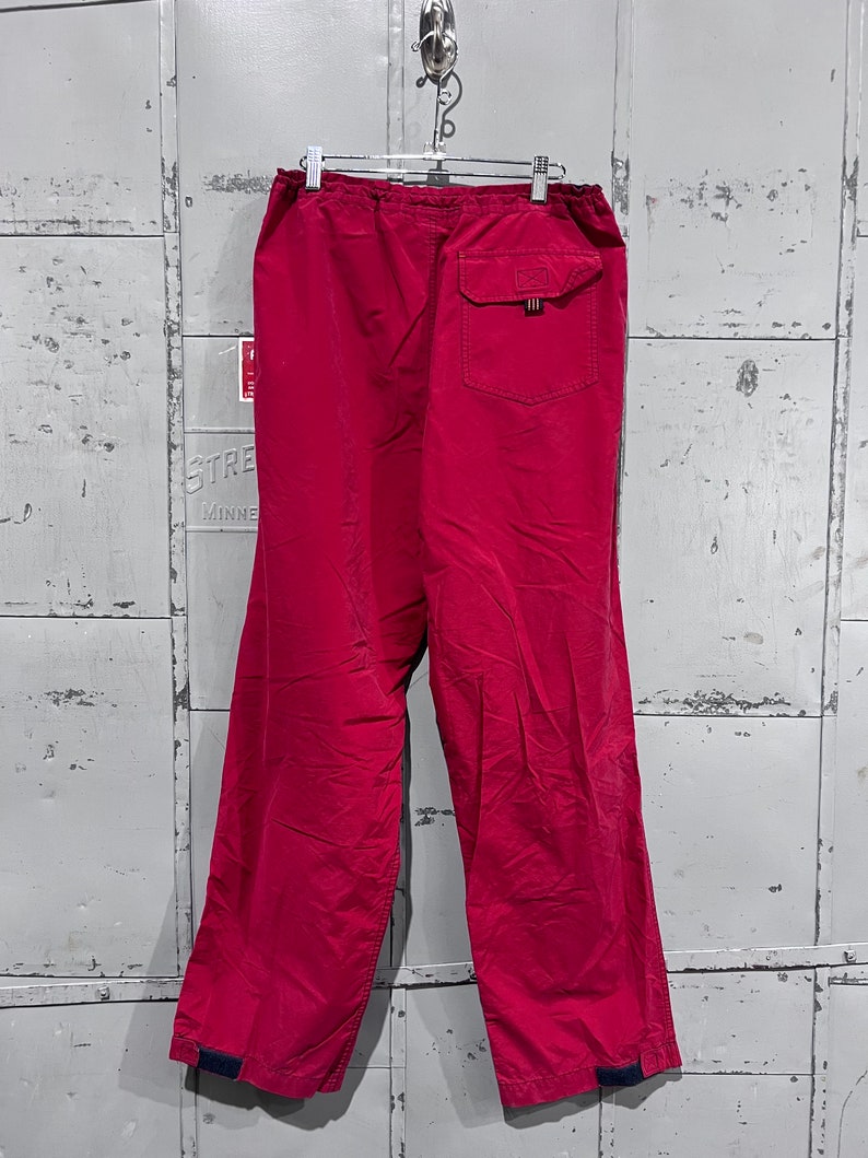 May include: A pair of red drawstring trousers with a single back pocket and elastic cuffs.