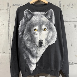 May include: Black sweatshirt with a large, detailed print of a wolf's face. The wolf has yellow eyes and a white and gray fur pattern.