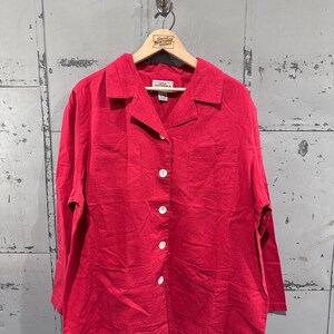 May include: A bright red button-down shirt with long sleeves and two front pockets. The shirt has a collared neckline and white buttons. The brand name "SONOMA" is visible on the label.
