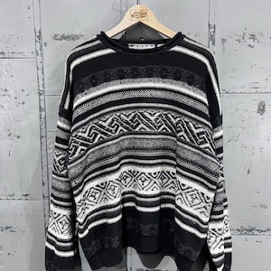 Puede incluir: Suéter a rayas blanco y negro con un patrón geométrico. El suéter tiene cuello redondo y mangas largas.