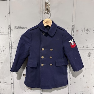 May include: A navy blue vintage coat with gold buttons and a small emblem on the sleeve. The coat has a double-breasted design and two front pockets. The coat is hanging on a wooden hanger.