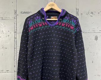 May include: Black knitted sweater with a purple, pink, and green patterned design. The sweater has a high neck and a button closure at the neck.
