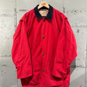 May include: A red, long-sleeved jacket with a corduroy collar and a plaid lining. The jacket has a button closure and two large pockets.